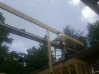 Carpenter setting a ridge beam over a new addition frame — Ice Dam Removal by Roofing Brothers in Saint Lucas