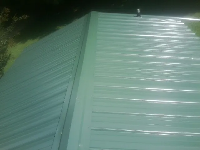 New green metal panels meeting at the ridge of a roof — Flat Roof Repair work by our crew in Saint Lucas