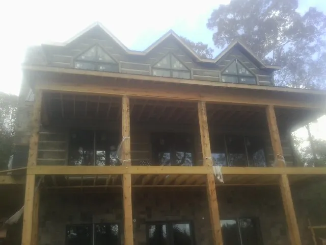 Dormers and porch framing on a large log home under construction — Roof Coating work by our crew in Saint Lucas