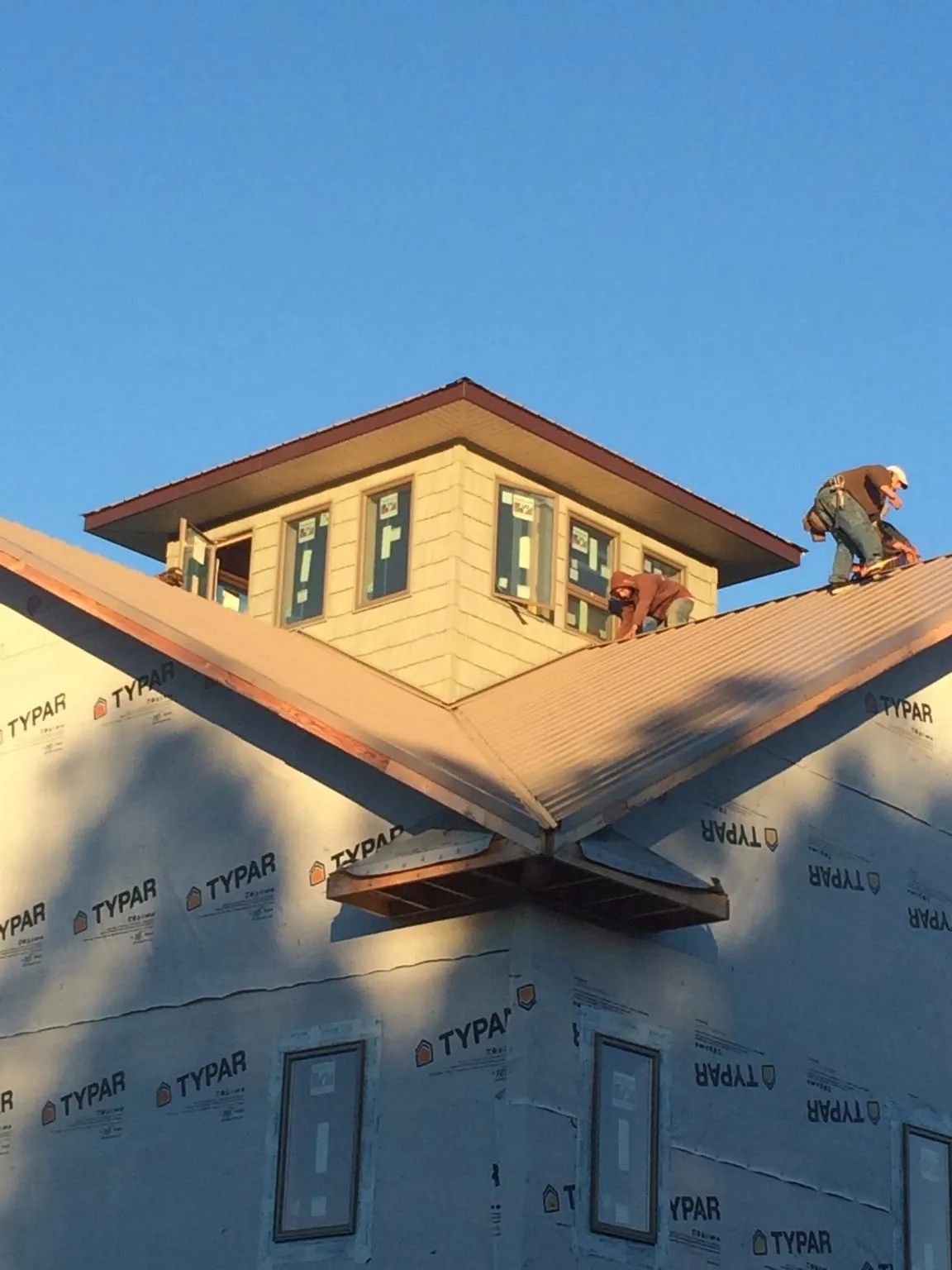 Roofers working around a rooftop cupola on a new metal roof at sunset — Roof Waterproofing in Saint Lucas by Roofing Brothers